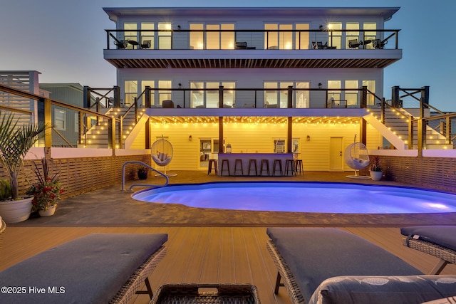 exterior space with a fenced in pool, stairs, and a balcony