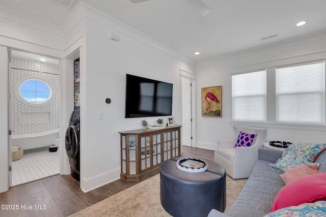 living area featuring visible vents, baseboards, wood finished floors, and ornamental molding