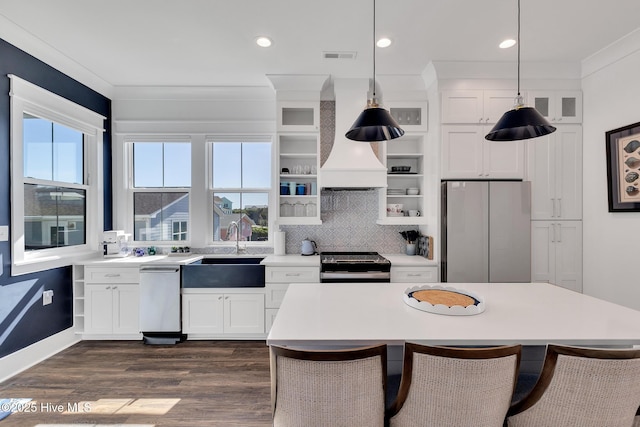 kitchen with a breakfast bar area, custom exhaust hood, a sink, stainless steel appliances, and light countertops