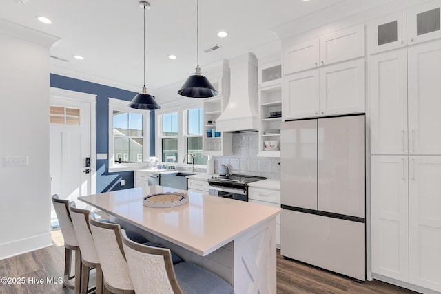 kitchen featuring visible vents, custom range hood, stainless steel appliances, white cabinetry, and open shelves