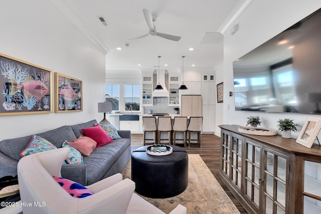 living area featuring visible vents, ceiling fan, dark wood-style flooring, and ornamental molding