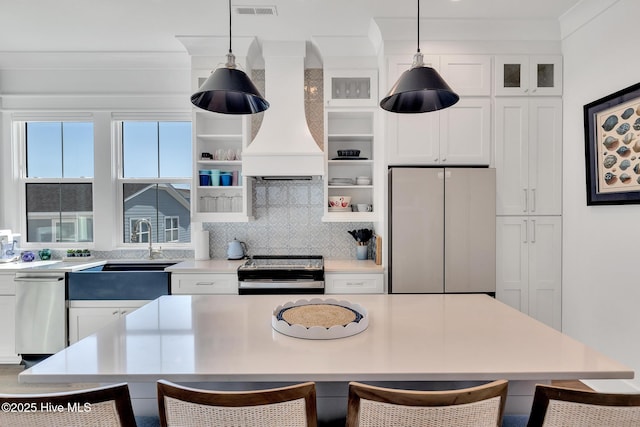 kitchen featuring a breakfast bar, custom exhaust hood, stainless steel appliances, light countertops, and backsplash