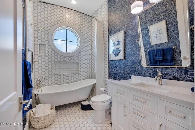 full bathroom featuring tile patterned floors, a freestanding tub, toilet, wallpapered walls, and vanity