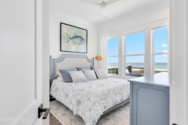 bedroom featuring ceiling fan, a water view, and wood finished floors