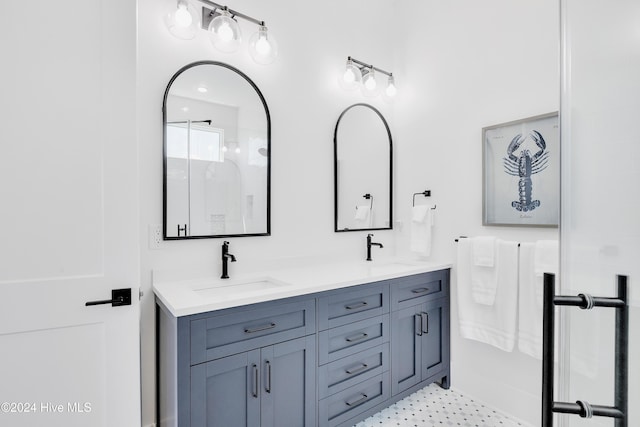 bathroom with a sink, a shower stall, and double vanity