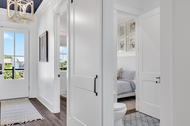 foyer entrance featuring dark wood-style floors, baseboards, and an inviting chandelier