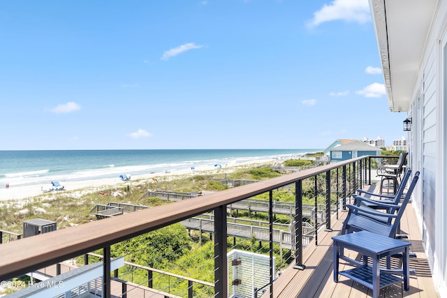 balcony with a water view and a view of the beach