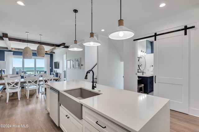 kitchen featuring a sink, open floor plan, a barn door, light wood finished floors, and dishwasher