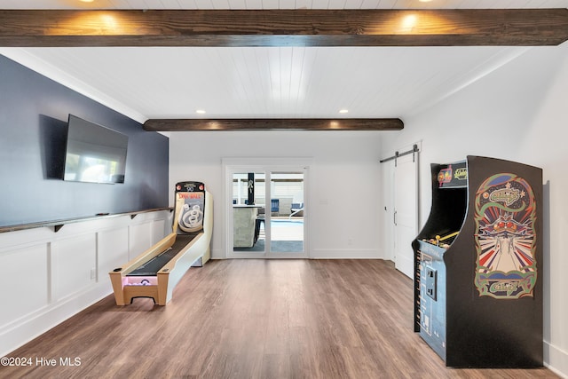 game room featuring beam ceiling, wainscoting, a barn door, and wood finished floors