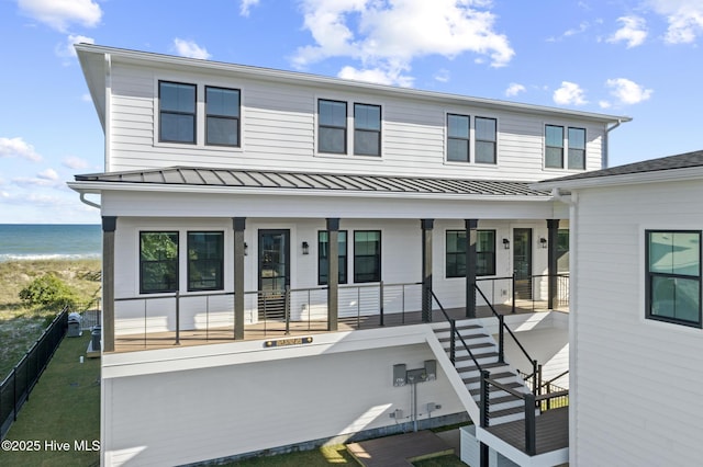 view of front of property featuring a water view, fence, covered porch, metal roof, and a standing seam roof