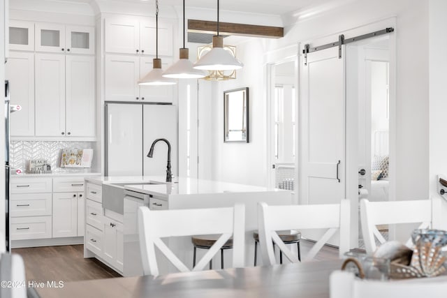 kitchen with dark wood-type flooring, a barn door, white appliances, white cabinets, and light countertops