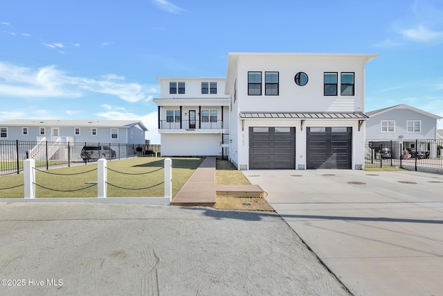 view of front facade featuring a front yard, fence, a standing seam roof, an attached garage, and concrete driveway