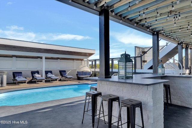 pool with a patio area, outdoor dry bar, and fence