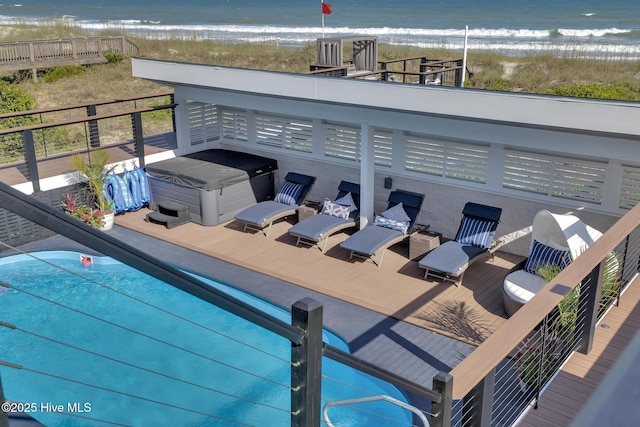 view of swimming pool with a beach view, a hot tub, and a deck with water view