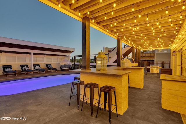 view of patio / terrace featuring stairway, fence, an outdoor pool, and outdoor dry bar