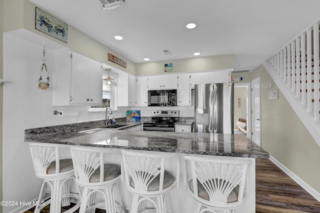 kitchen featuring sink, dark stone countertops, stainless steel appliances, white cabinets, and kitchen peninsula