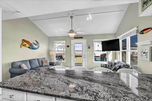 kitchen featuring white cabinetry, vaulted ceiling, dark stone counters, and ceiling fan