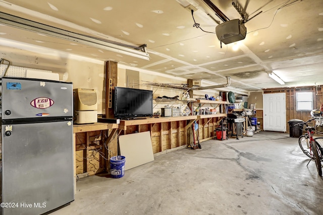 garage featuring a garage door opener, stainless steel fridge, and a workshop area