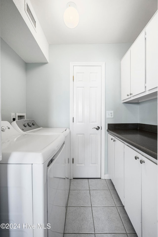 laundry area with independent washer and dryer, cabinets, and light tile patterned floors