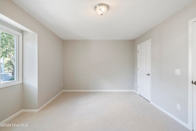 unfurnished room featuring light colored carpet