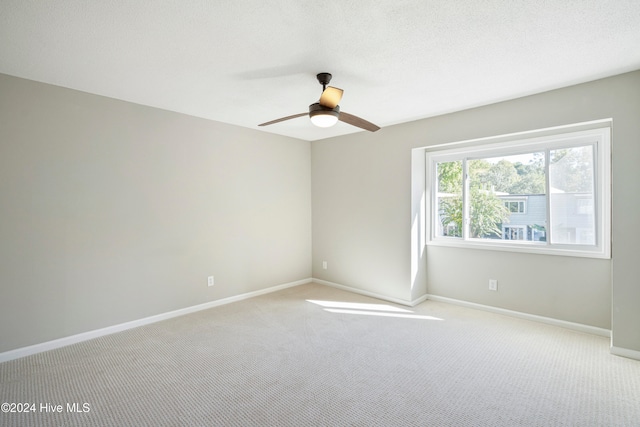 carpeted spare room featuring ceiling fan and a textured ceiling