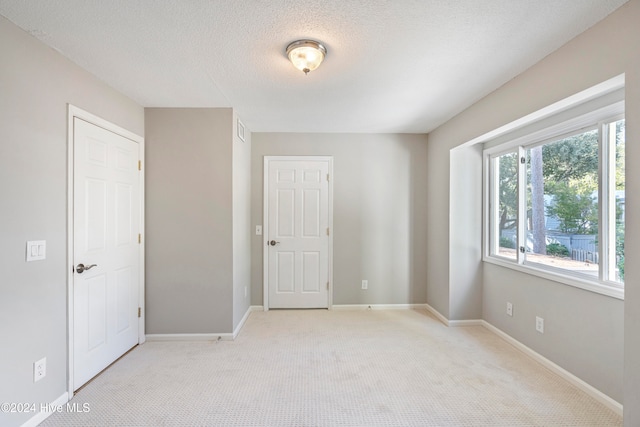 spare room featuring light carpet and a textured ceiling