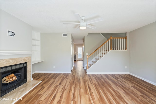 unfurnished living room with hardwood / wood-style floors, a textured ceiling, a tile fireplace, and ceiling fan