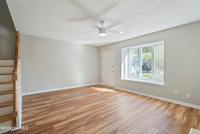 unfurnished room featuring a textured ceiling, light wood-type flooring, and ceiling fan