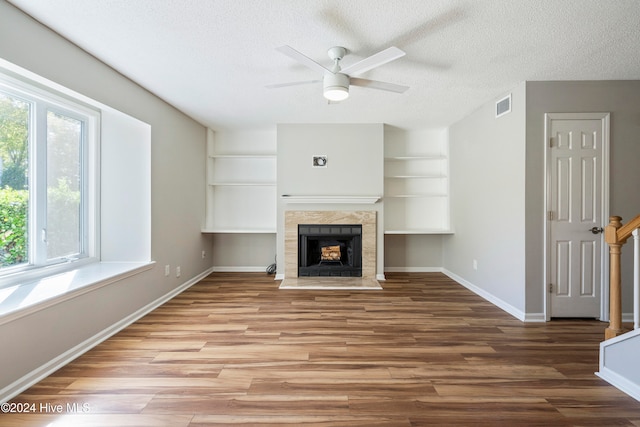 unfurnished living room with ceiling fan, wood-type flooring, a textured ceiling, and a fireplace