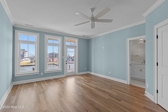 empty room featuring light wood-type flooring, ceiling fan, and crown molding