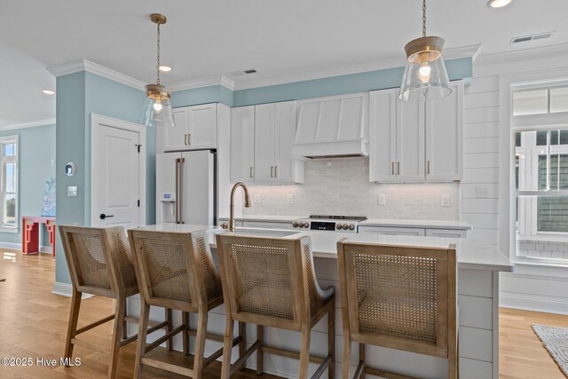 kitchen with sink, stainless steel appliances, an island with sink, light hardwood / wood-style floors, and white cabinets