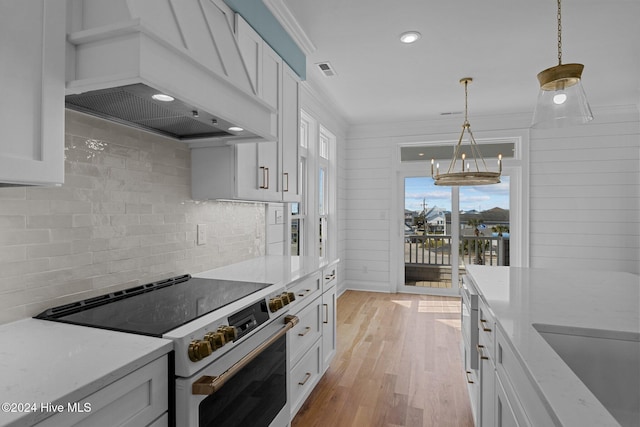 kitchen with premium range hood, white cabinetry, high end range, and light stone counters