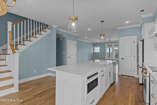 kitchen with a center island with sink, white cabinetry, sink, and light hardwood / wood-style flooring