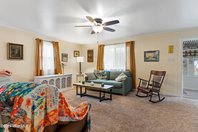 living room with ceiling fan, ornamental molding, and light carpet