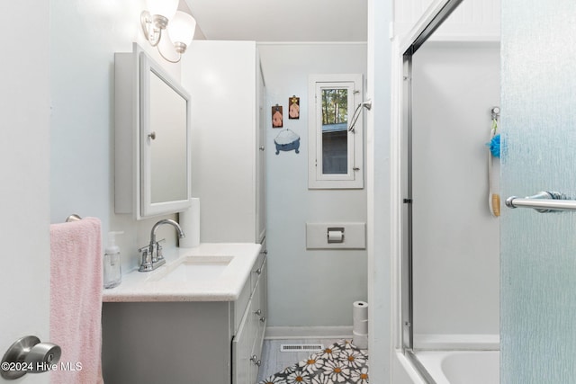 bathroom with combined bath / shower with glass door, vanity, and tile patterned flooring