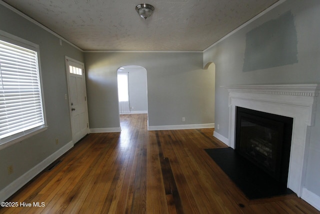 unfurnished living room featuring dark hardwood / wood-style flooring, ornamental molding, and a textured ceiling