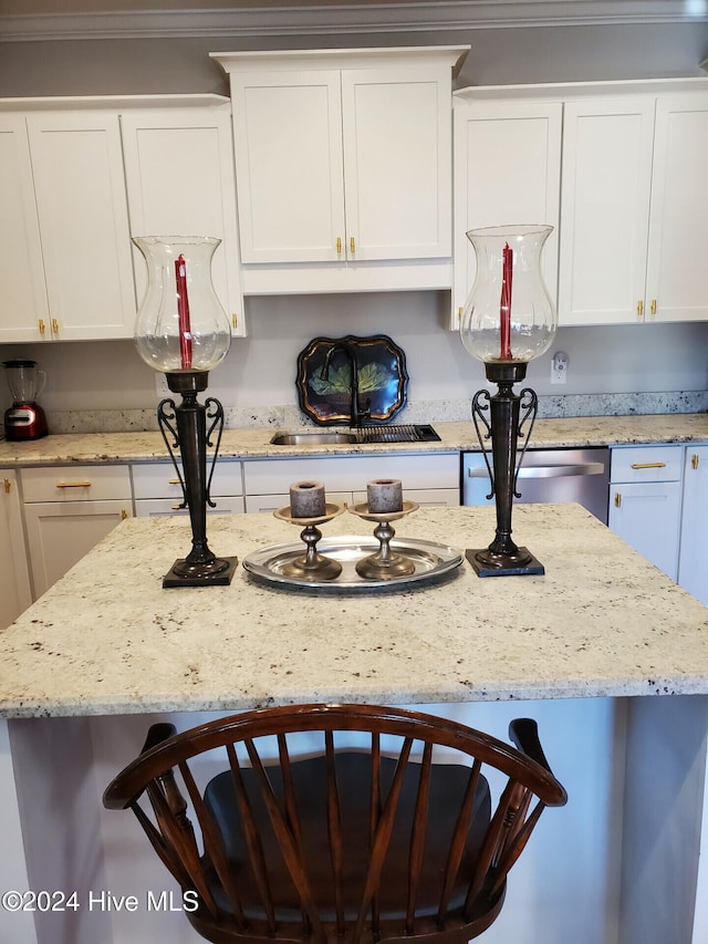 kitchen featuring crown molding, sink, a kitchen bar, and white cabinets