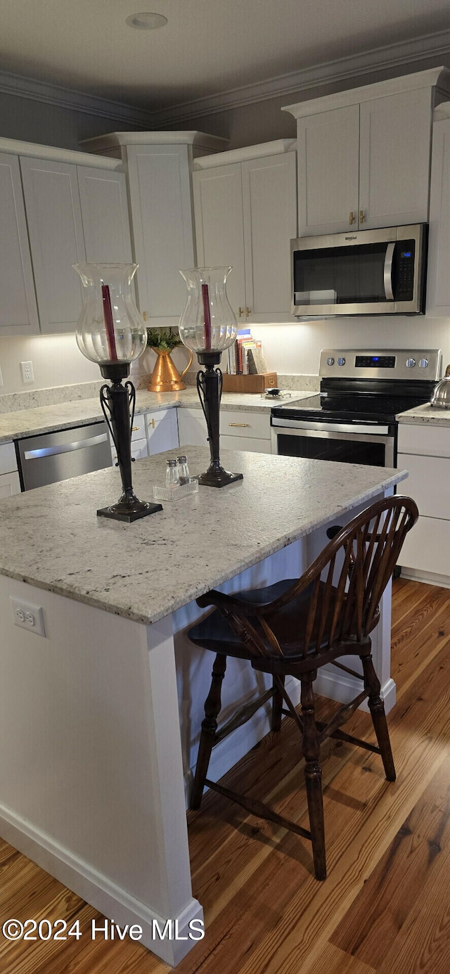 kitchen featuring crown molding, white cabinets, stainless steel appliances, and hardwood / wood-style flooring