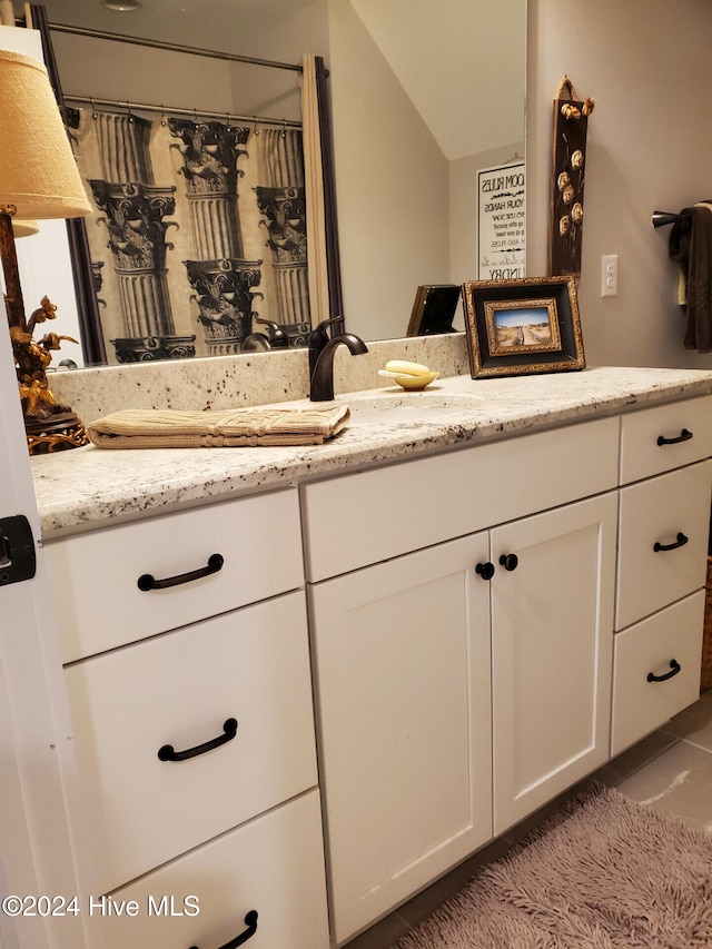 bathroom featuring vanity, lofted ceiling, and tile patterned flooring