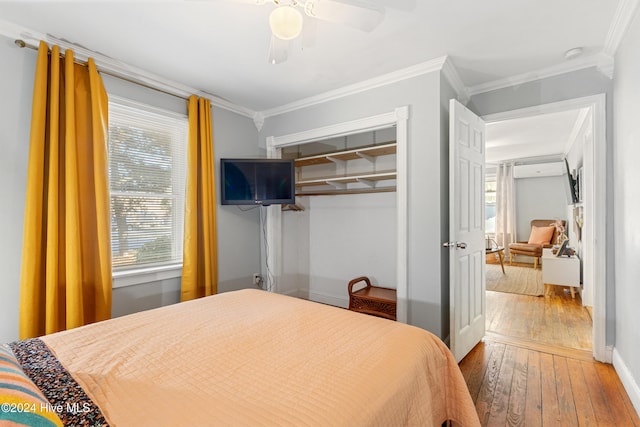 bedroom featuring wood-type flooring, a closet, crown molding, and ceiling fan