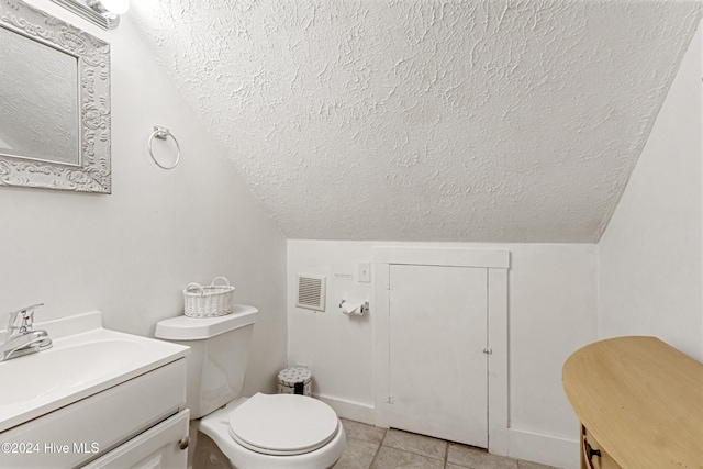 bathroom with vanity, a textured ceiling, tile patterned flooring, toilet, and lofted ceiling