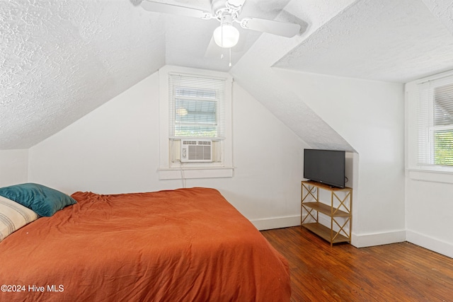 bedroom with hardwood / wood-style floors, a textured ceiling, vaulted ceiling, and ceiling fan