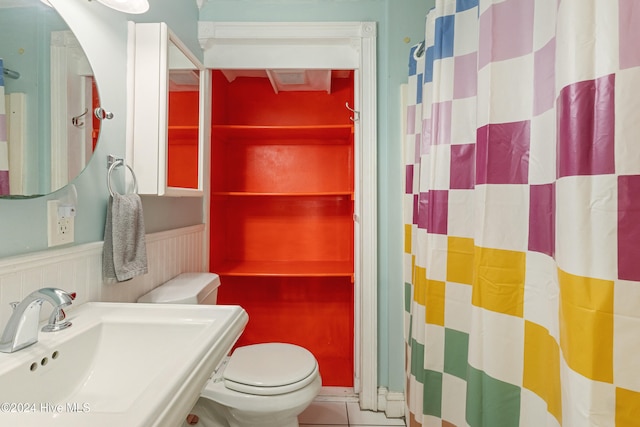 bathroom featuring toilet, sink, and tile patterned flooring