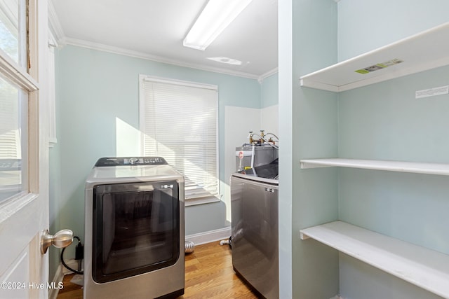 laundry room featuring independent washer and dryer, light hardwood / wood-style flooring, ornamental molding, and water heater