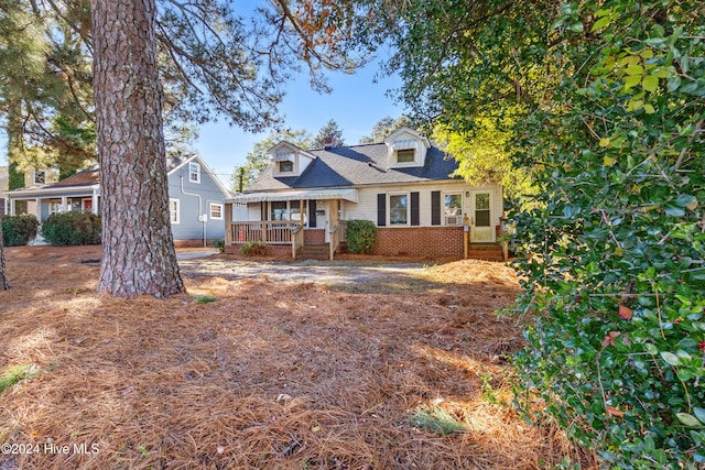 cape cod home featuring covered porch