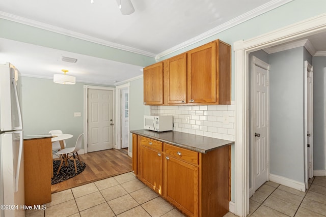 kitchen with white appliances, light hardwood / wood-style flooring, crown molding, and backsplash