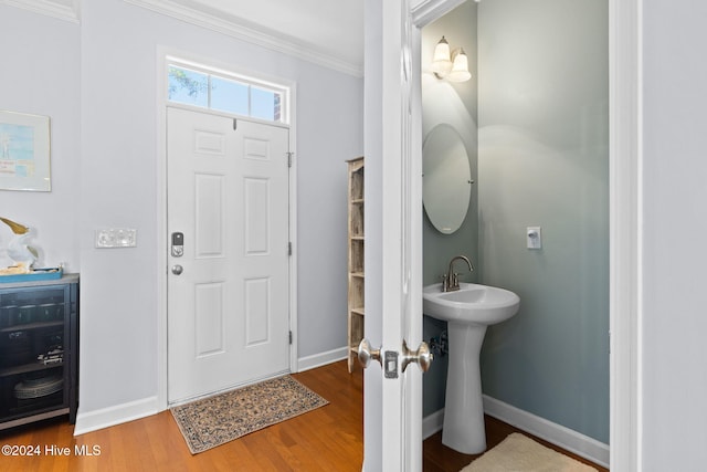 foyer entrance featuring sink, beverage cooler, ornamental molding, and hardwood / wood-style flooring