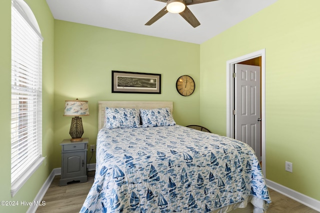 bedroom with light wood-type flooring, ceiling fan, and multiple windows