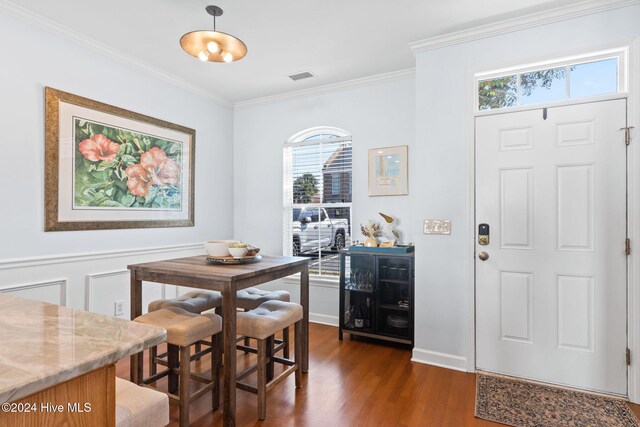 dining area featuring dark wood-type flooring and ornamental molding