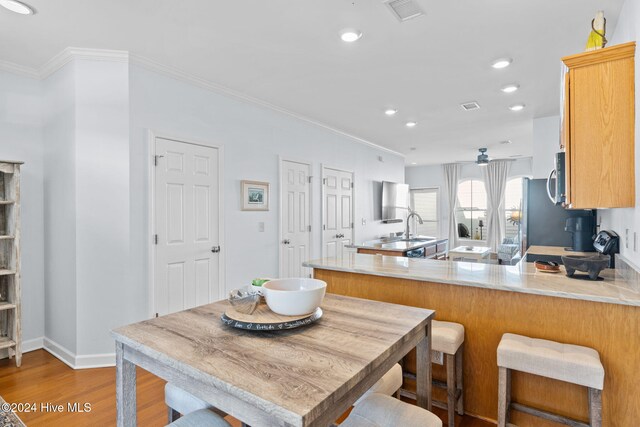 kitchen with kitchen peninsula, sink, ornamental molding, and hardwood / wood-style floors